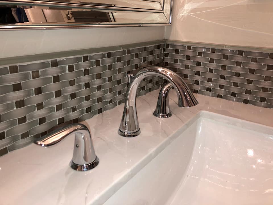 Bathroom sink backsplash tile installation.